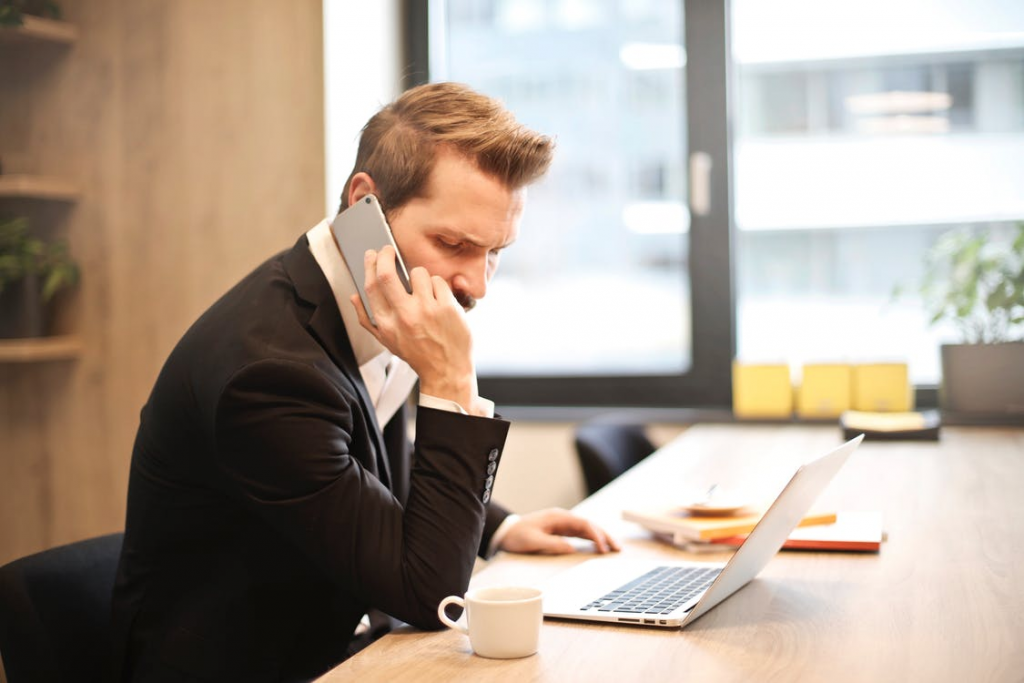 A man sitting at a desk speaking on the phone